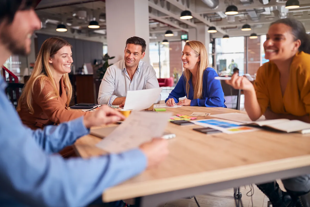 A group of people sitting around a table in an office.